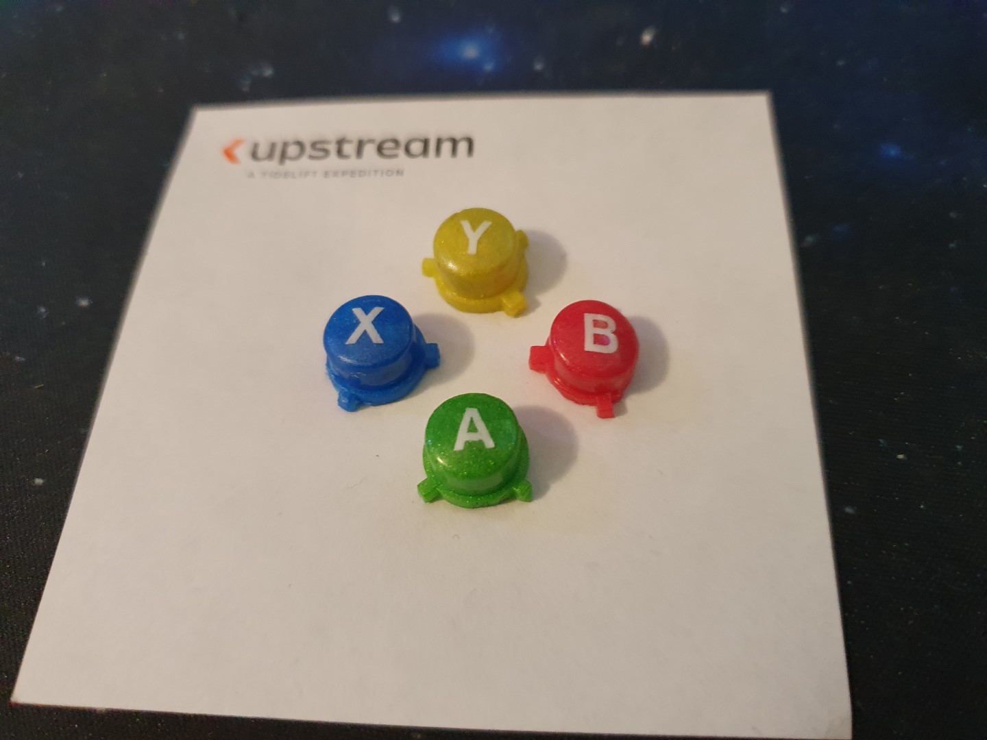 The four custom buttons sitting on a post-it note.